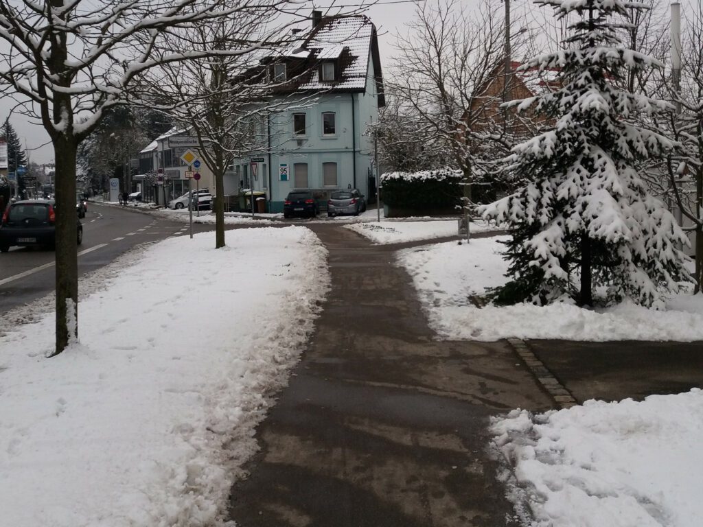Chão coberto de neve com caminho aberto para passagem de pedestres na calçada.