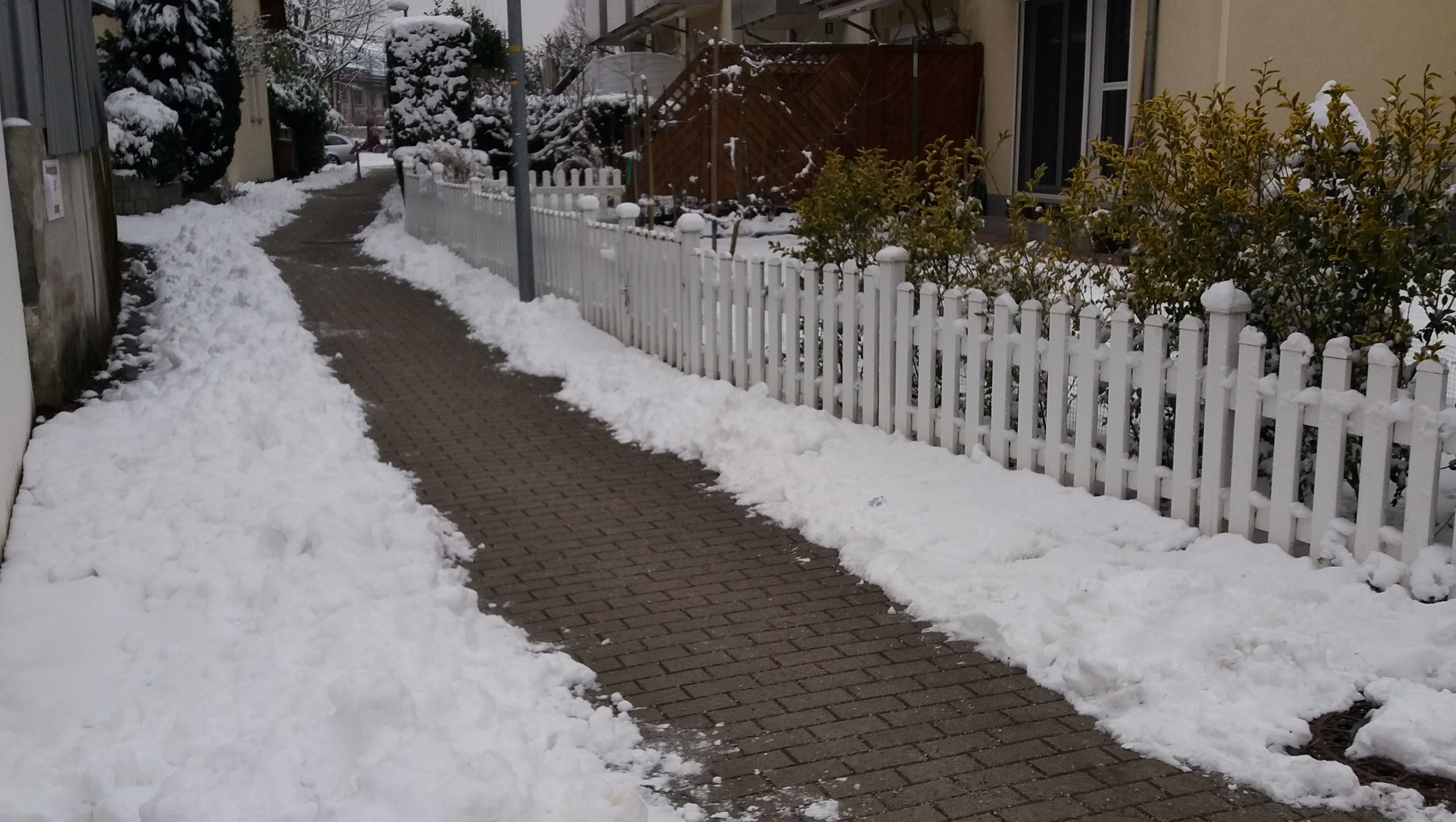 Chão coberto de neve com caminho aberto para passagem de pedestres na calçada.